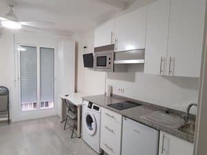 Cocina con muebles blancos y puerta balconera