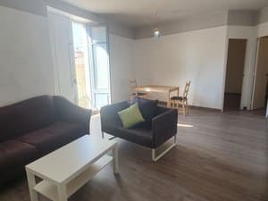 Salón con sofás, mesa baja y comedor junto al balcón
