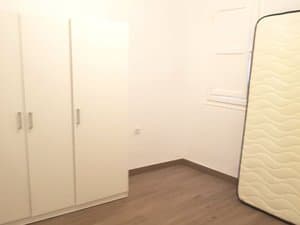 Dormitorio con armario blanco y colchón