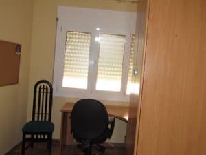 Dormitorio con escritorio y silla junto a la ventana