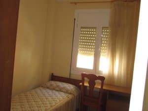 Dormitorio con cama individual y silla