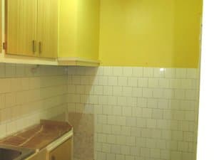 Cocina con azulejos blancos y armarios altos