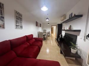 Salón alargado con sofá y comedor al fondo
