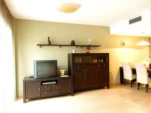 Salón con mueble de televisión y comedor al fondo