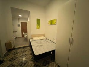 Zona de dormitorio con armario blanco y suelo hidráulico