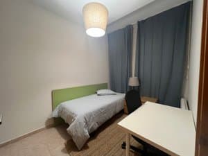 Habitación con cama y escritorio junto a la ventana