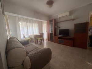 Salón comedor con sofá, mueble de televisión y aire acondicionado