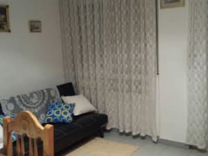 Salón con sofá negro y cortinas