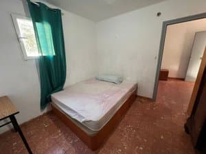Dormitorio con cama y ventana con cortina verde