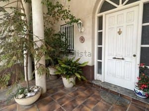 Entrada de la casa con puerta blanca y plantas