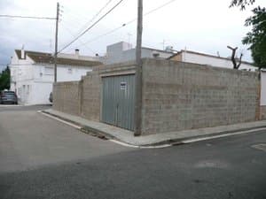 Muro del solar con puerta metálica en la esquina
