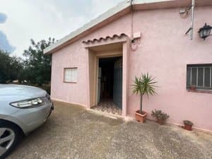 Fachada rosa de la casa con coche aparcado