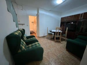 Salón con butacas verdes y comedor al fondo