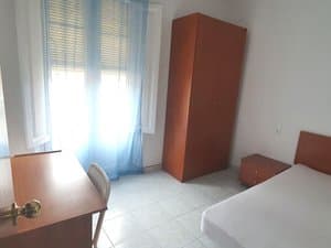 Dormitorio con cama y escritorio junto a la ventana
