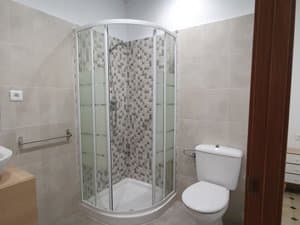 Baño con ducha de mampara e inodoro