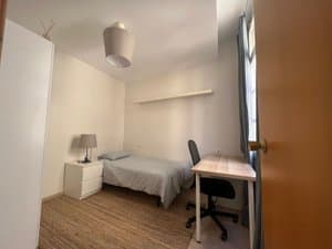 Habitación con cama y escritorio junto a la puerta