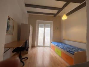 Estudio con vigas de madera y cama individual