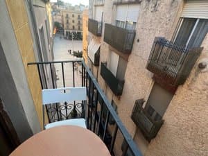 Balcón con mesa y silla sobre la calle