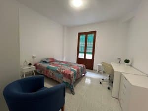 Dormitorio con cama, butaca azul y escritorio