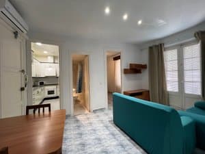 Salón con sofá turquesa y puerta a la cocina