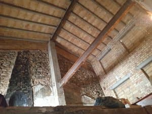 Interior con vigas de madera y muros de piedra