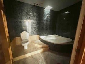 Baño con bañera de hidromasaje y paredes oscuras