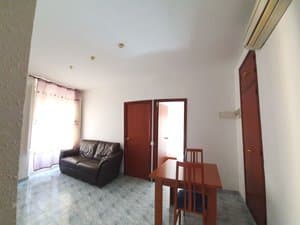 Salón con sofá negro y aire acondicionado
