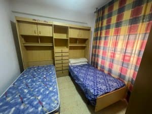 Dormitorio con dos camas y mueble de estantes