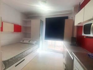 Estudio con cama junto a la ventana y cocina