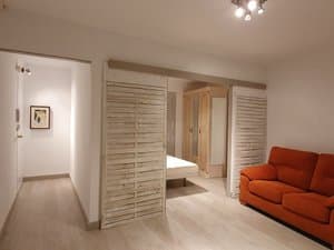 Salón con sofá y paneles de madera que separan el dormitorio