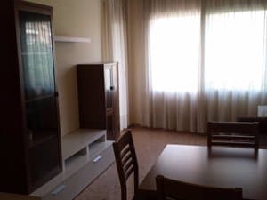 Salón con mueble de madera y mesa junto al ventanal
