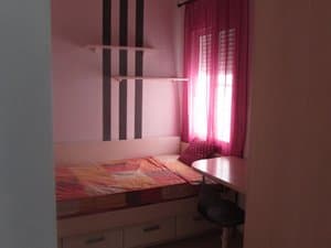 Dormitorio con cama y escritorio junto a la ventana