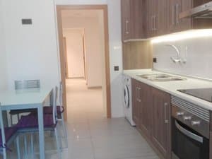 Cocina moderna con horno, lavadora y mesa