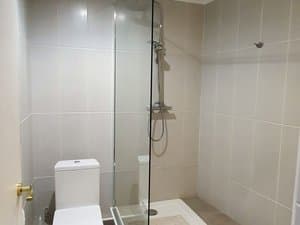 Baño con ducha de mampara e inodoro