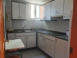 Cocina con muebles blancos y mesa plegable