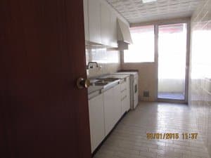 Cocina con muebles blancos y salida al balcón