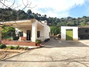 Casa de una planta con porche y almacén
