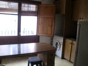 Cocina con mesa, lavadora y frigorífico