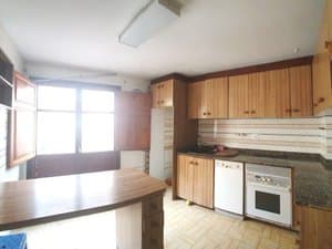 Cocina con muebles de madera, barra y ventana