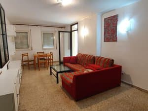 Salón con sofá rinconera, mesa de comedor y ventanas