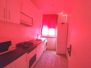 Cocina con muebles blancos, lavadora y ventana