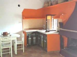 Cocina con muebles naranjas, mesa y chimenea