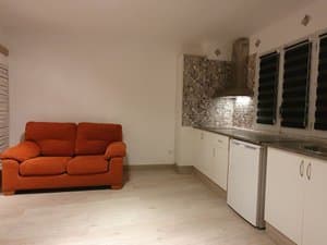 Salón con sofá junto a la cocina