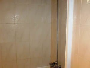 Baño alicatado con bañera y grifería de ducha