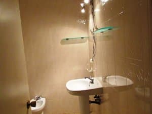 Baño con lavabo, bidé y estantes de cristal