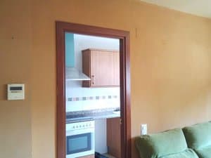 Salón con sofá y puerta a la cocina
