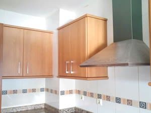 Cocina con muebles altos de madera y campana