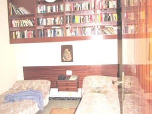 Dormitorio con dos camas y estantería con libros