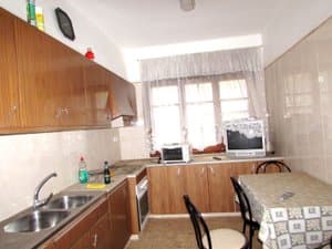 Cocina con muebles de madera, fregadero doble y mesa