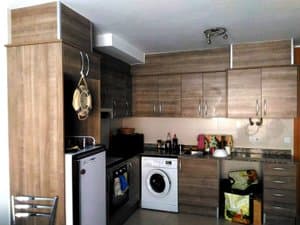 Cocina con muebles de madera, horno y lavadora